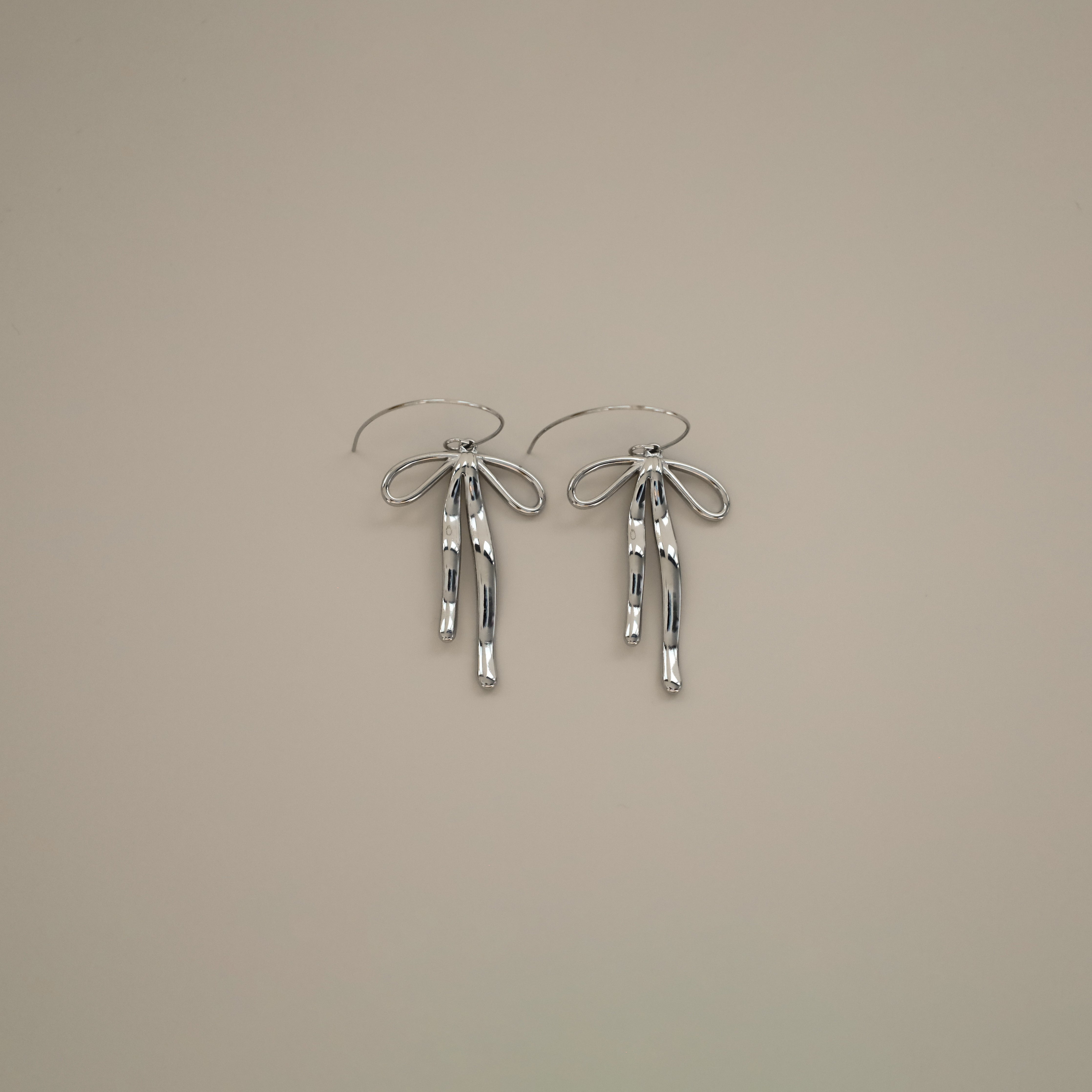 erkinne silver earrings, delicate bow design with dangling ribbons on model