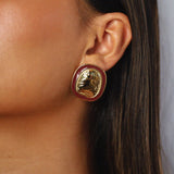 ekatt earrings, gold unique organic shape with a smooth, polished surface and subtle, engraved line designs with a wine red border