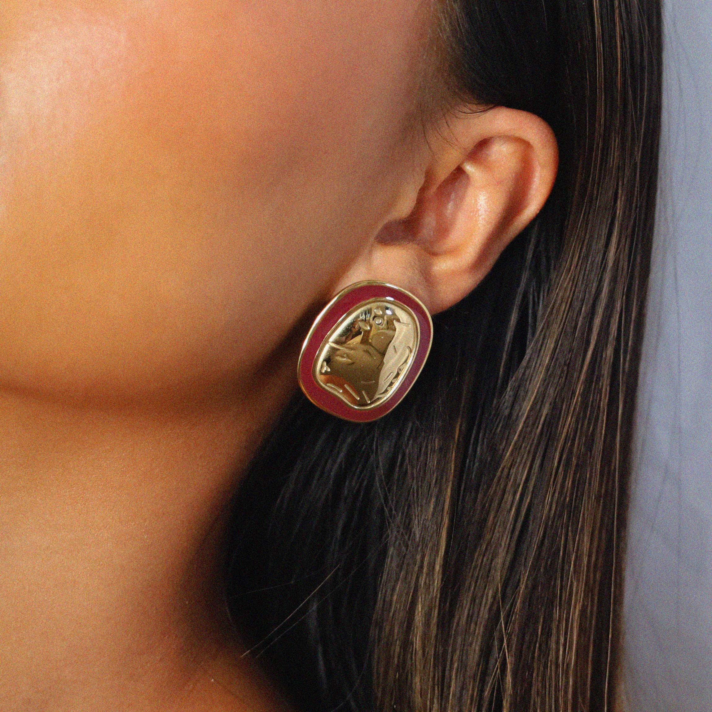 ekatt earrings, gold unique organic shape with a smooth, polished surface and subtle, engraved line designs with a wine red border