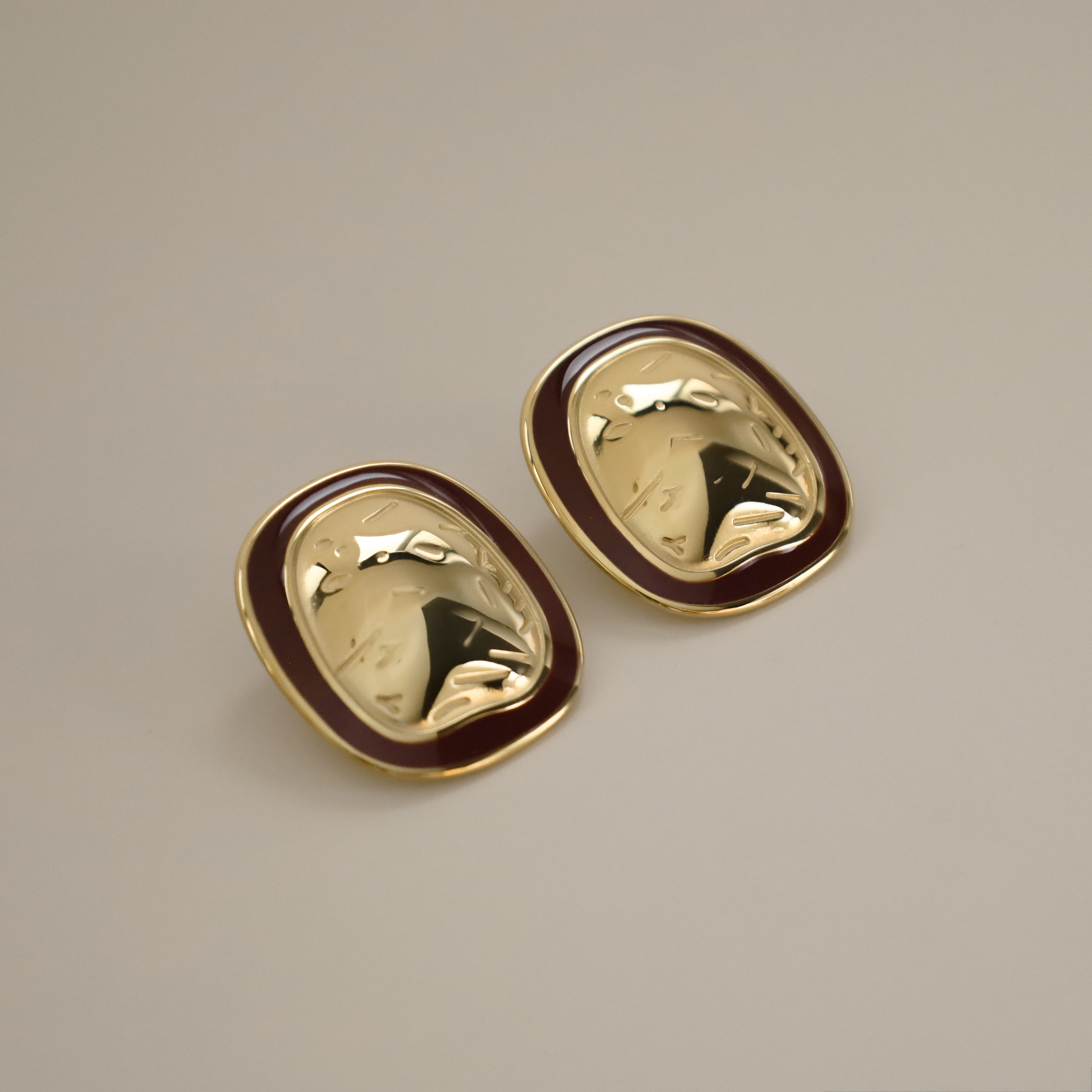 ekatt earrings, gold unique organic shape with a smooth, polished surface and subtle, engraved line designs with a wine red border