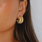 elluana hoops, thick gold hoop with a ribbed texture on model