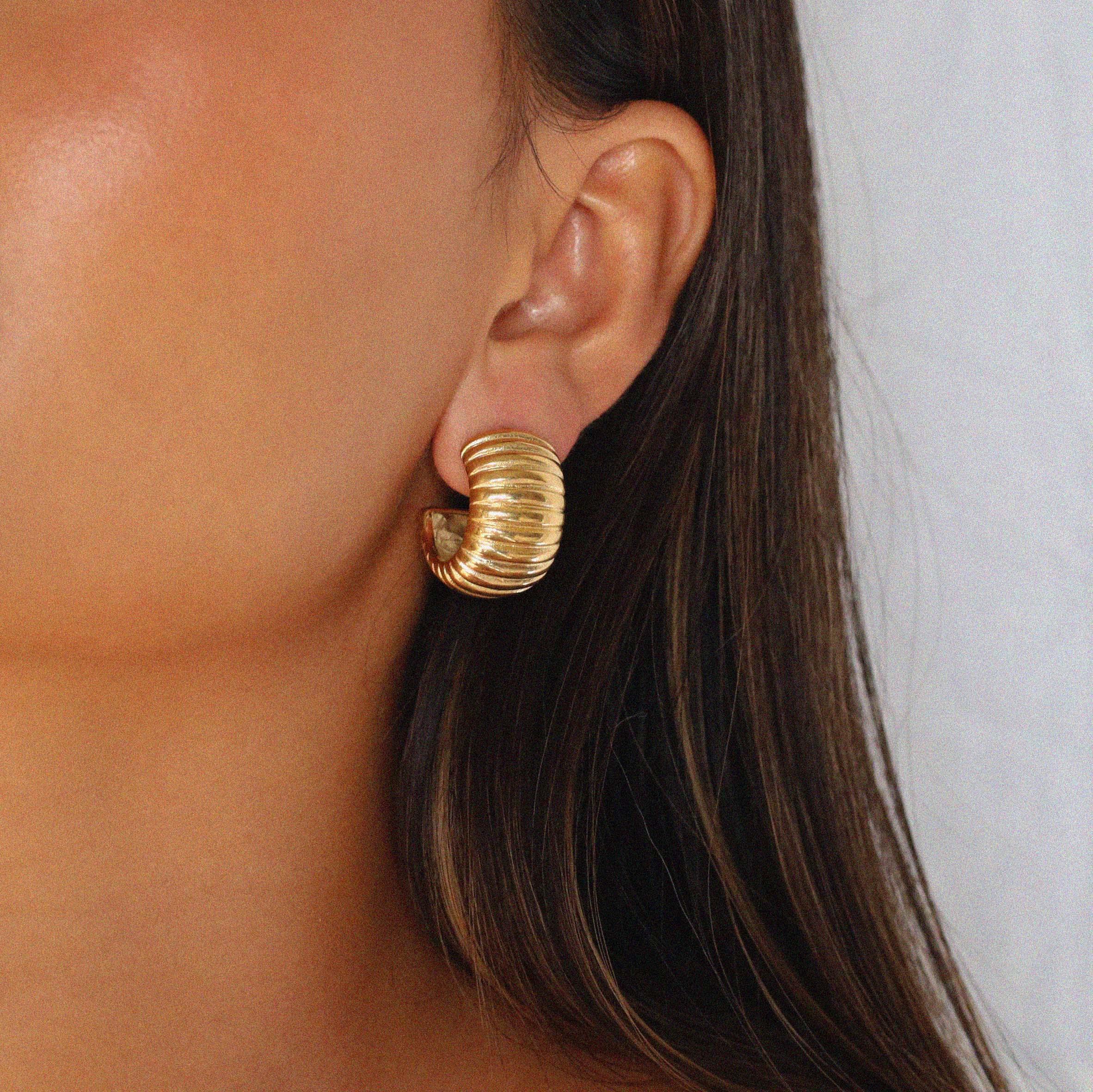 elluana hoops, thick gold hoop with a ribbed texture on model