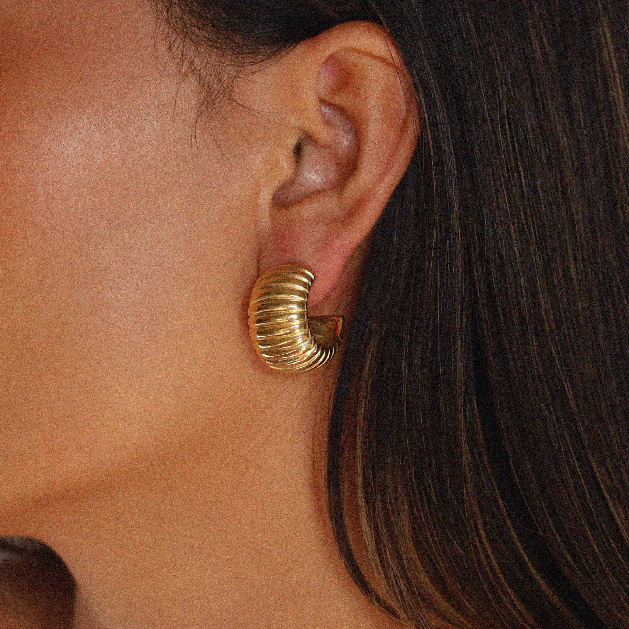 elluana hoops, thick gold hoop with a ribbed texture on model