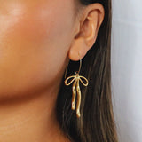 erkinne gold earrings, delicate bow design with dangling ribbons on model