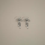 erkinne silver earrings, delicate bow design with dangling ribbons on model