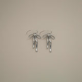 erkinne silver earrings, delicate bow design with dangling ribbons on model