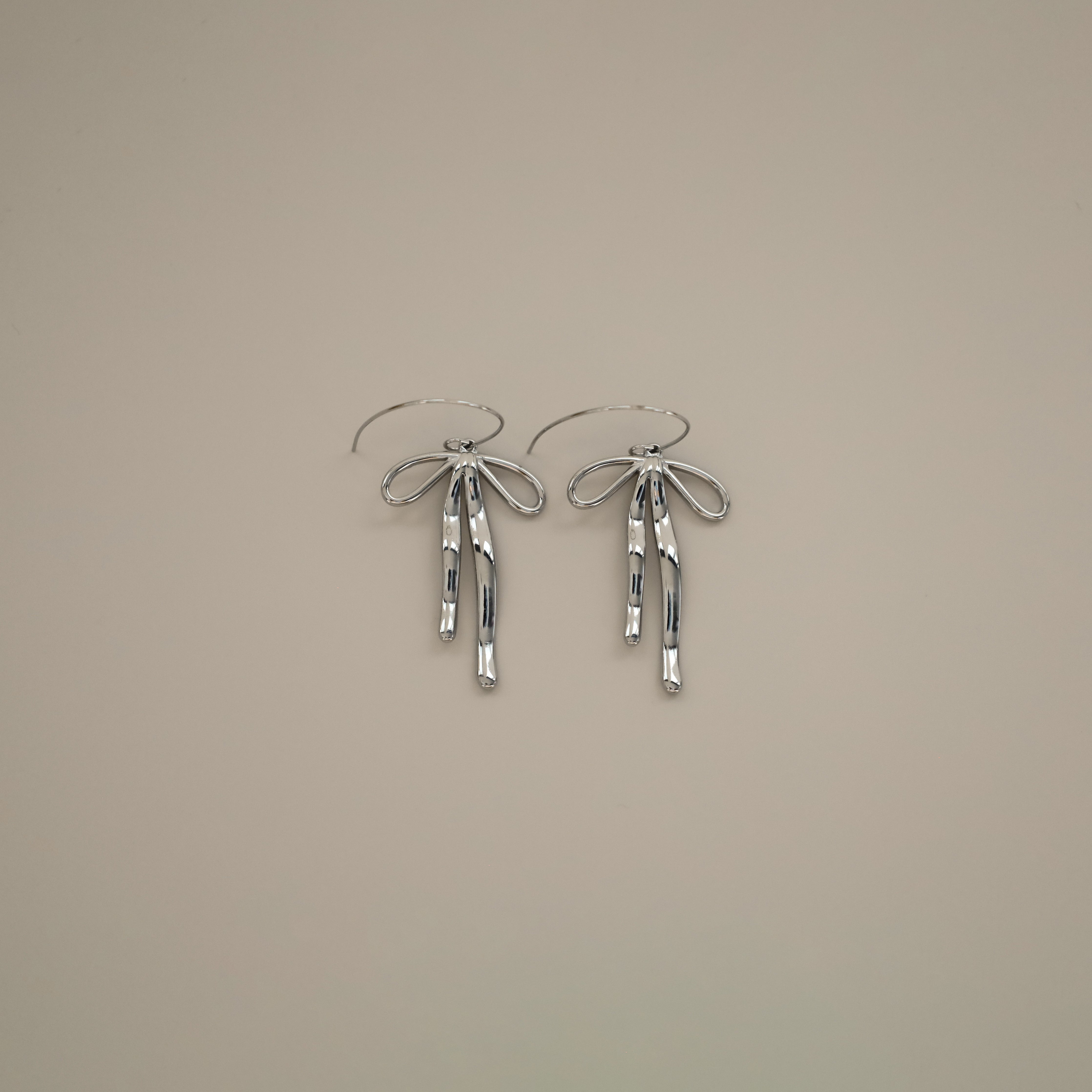 erkinne silver earrings, delicate bow design with dangling ribbons on model