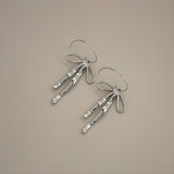 erkinne silver earrings, delicate bow design with dangling ribbons on model