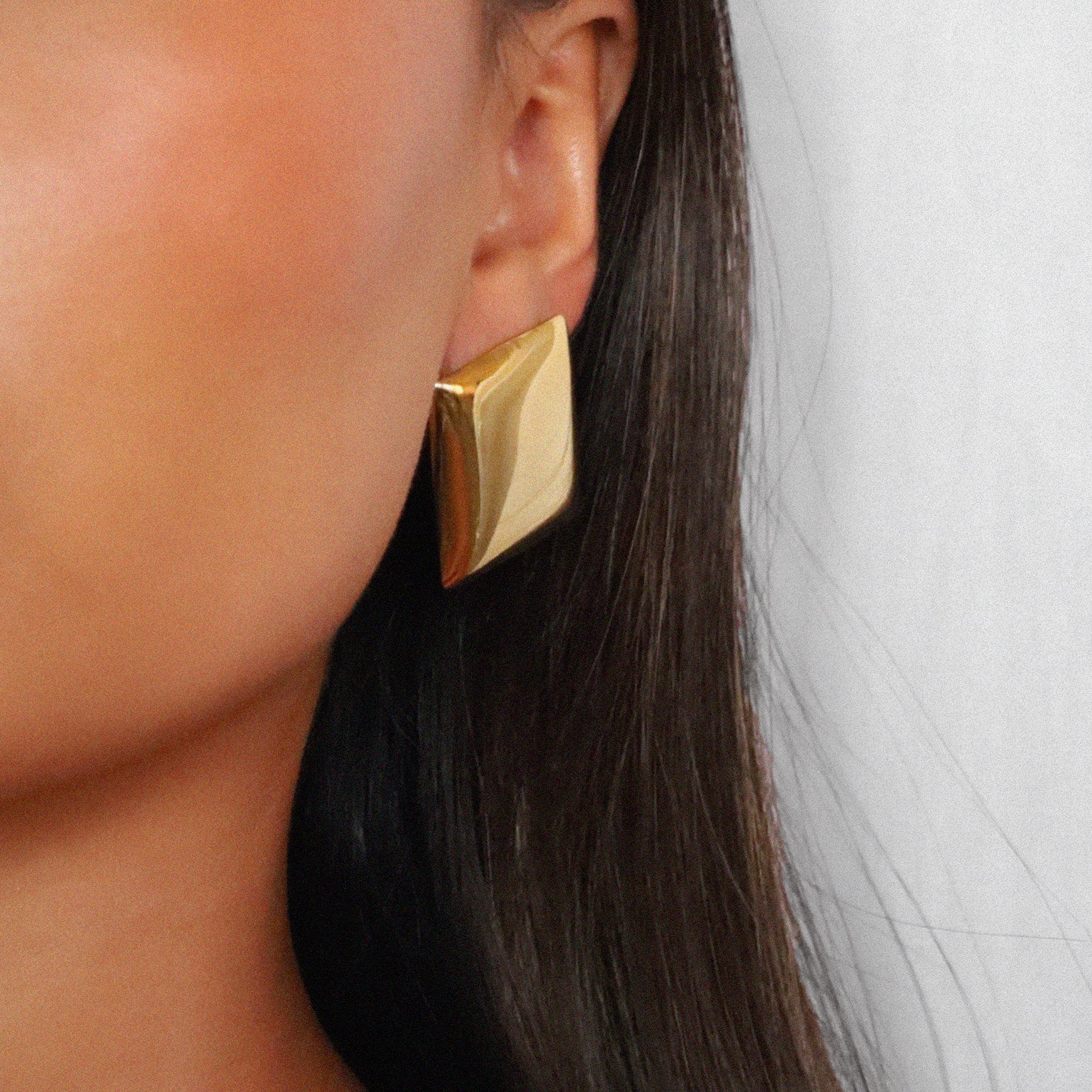 evrim earrings, gold bold rectangle design with a smooth domed surface