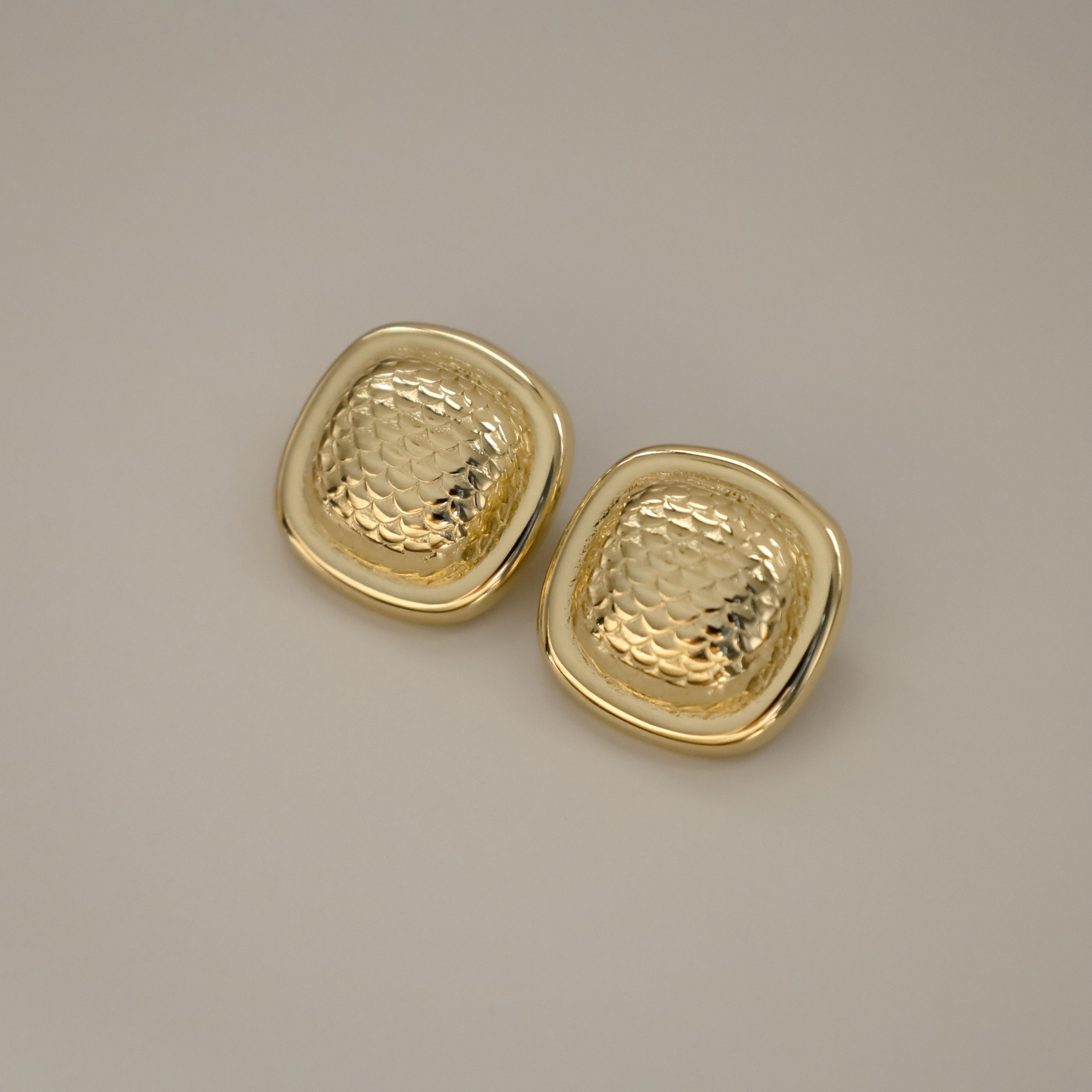 ezana earrings, gold rectangular earrings with puffy center in a scale design and smooth outer edge